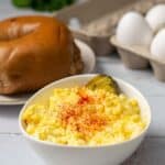 deli egg salad in a white bowl with a bagel on the side