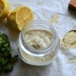 Tahini Sauce in a jar with lemons on the side