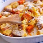 Sweet Potato Bread Pudding in a white bowl with a wooden spoon in the middle