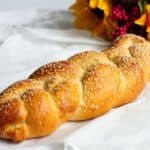 Traditional Challah Bread on a white cloth with flowers behind