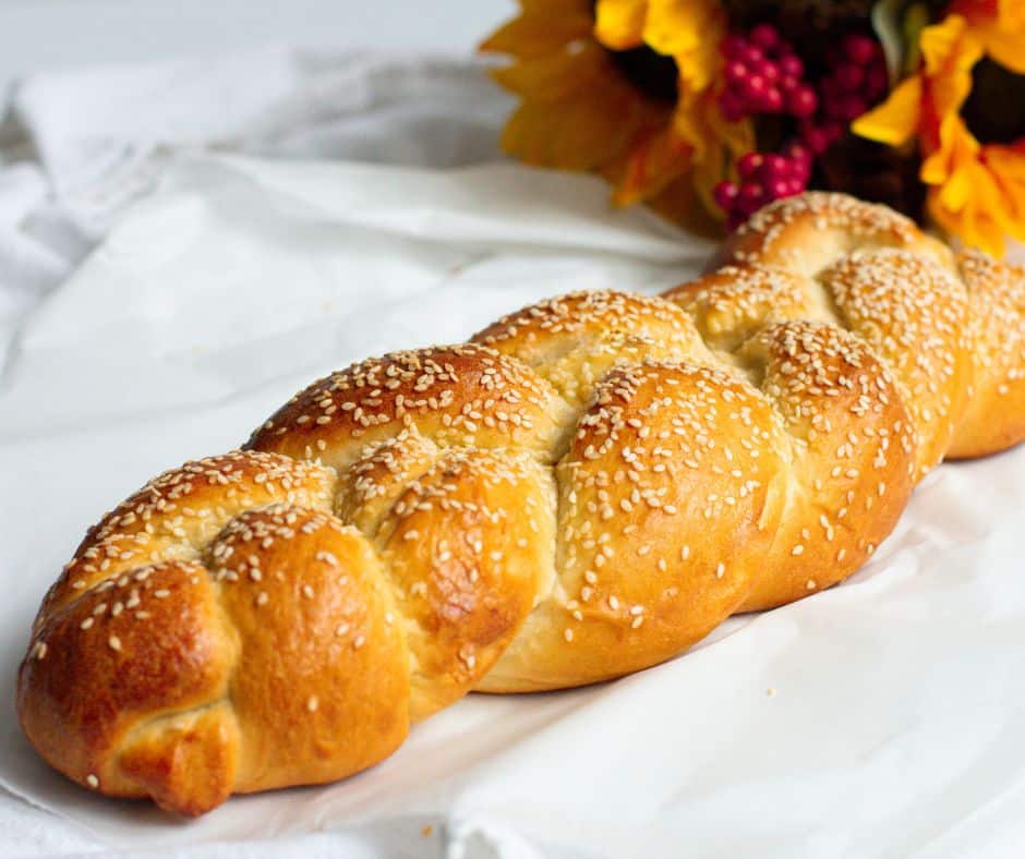 Traditional Challah Bread on a white cloth with flowers behind