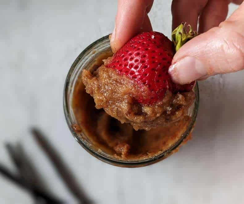 Healthy Caramel Dip a fingure holding strawberry