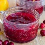 cranberry sauce in a clear glass with cranberries on the side