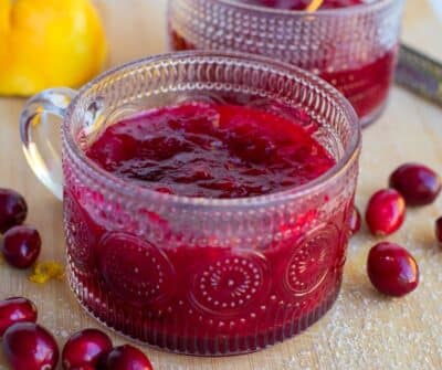 cranberry sauce in a clear glass with cranberries on the side