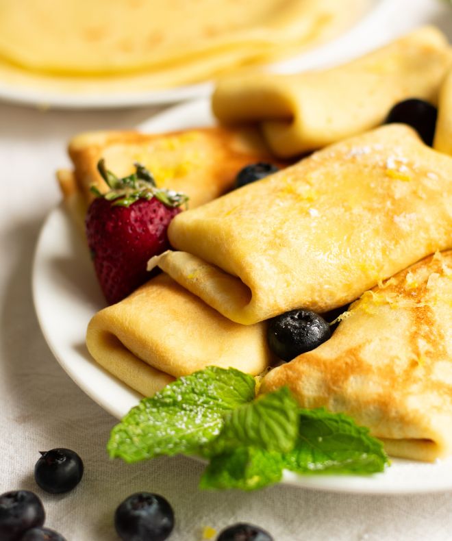 Sweet Cheese Blintzes with berries on a white plate