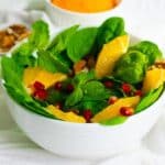 spinach pomegranate salad in a white bowl