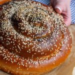 A hand holing a round Challah