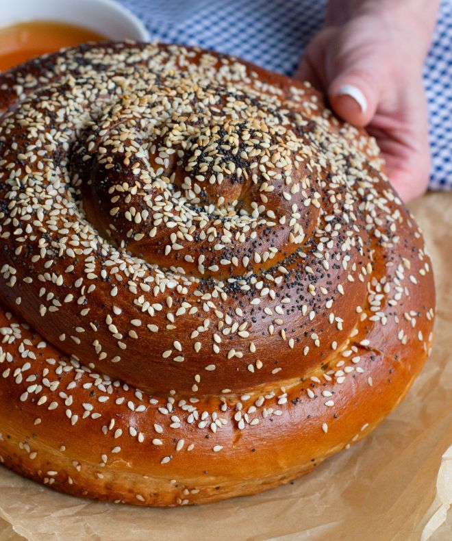 A hand holing a round Challah