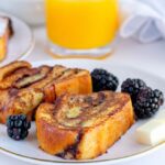 Babka French Toast on a plate with orange juice and black berries