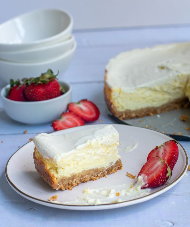 Baked Cheesecake slice on a white plate with strawberries