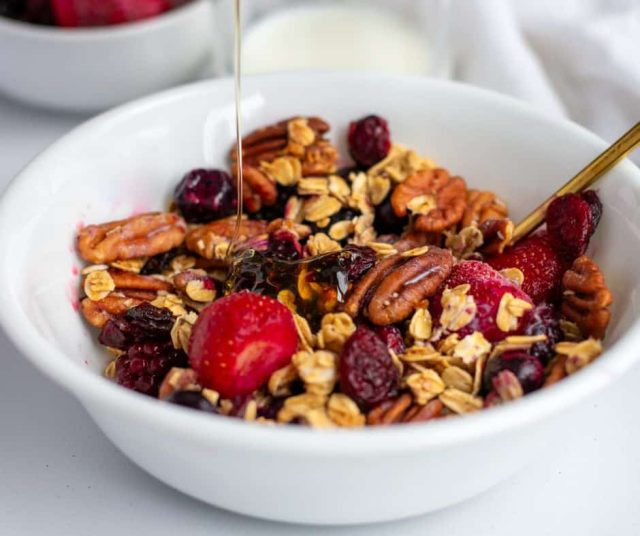 Maple Pecan Granola in a white bowl with berries