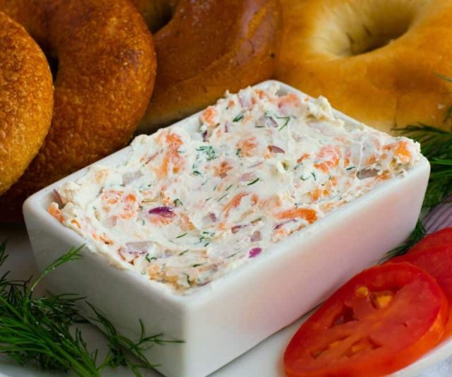 lox spread in a white bowl with bagels and veggies on the side