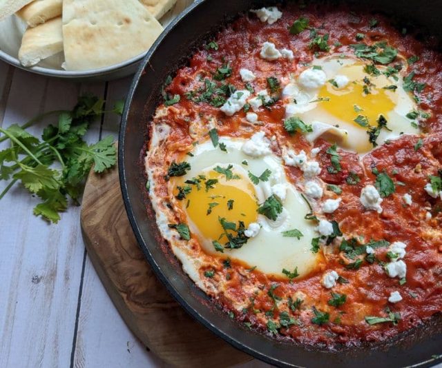 shakshuka in a black pan with bread on the side